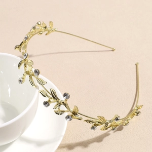 Détail d'un serre-tête feuilles dorées avec strass posé sur une tasse en céramique