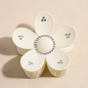 Détail de la pince à cheveux fleur crème avec centres en strass et accents de pétales