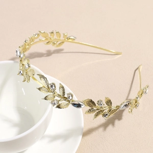 Détail d'un serre-tête feuilles en métal doré avec cristaux sur le bord d'une tasse