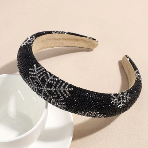 Close-up of black sponge headband with rhinestone snowflake pattern on white cup