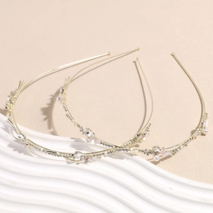 Elegant gold headband set with pink flowers and pearls on a white decorative stand