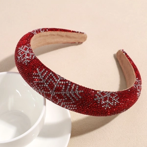 Close-up of a wide red padded headband with sparkling rhinestone snowflakes on a light base