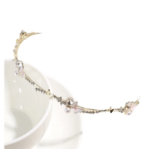Elegant gold headband with pink butterfly, pearls and rhinestones on a ceramic cup