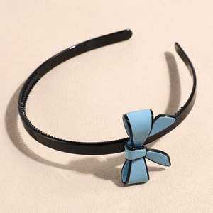 Detail of black non-slip headband with fine inner teeth and a 3D light blue bow accent