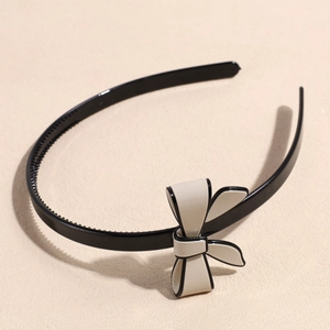 Detail view of non-slip teeth on a black headband with a cream-white bow accessory