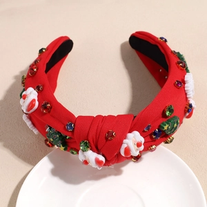 Détail d'un serre-tête de Noël rouge avec motifs Père Noël et strass colorés brillants
