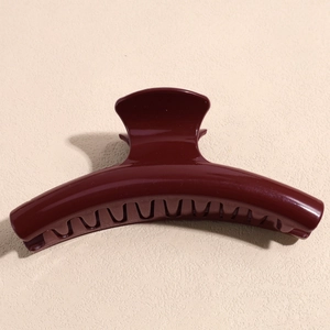Macro view of a large burgundy resin hair claw clip with a glossy finish and rounded teeth