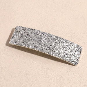 Dettaglio del fermaglio per capelli rettangolare in metallo argento con texture metallica