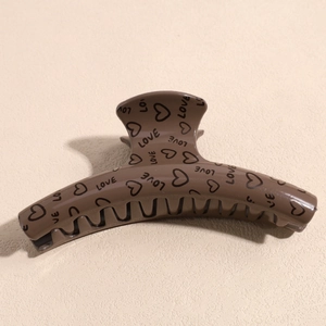 Detail of coffee brown large hair claw clip with heart patterns and LOVE text print