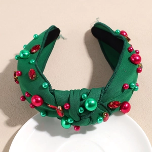 Gros plan d'un serre-tête noué vert avec strass rouges et perles de Noël