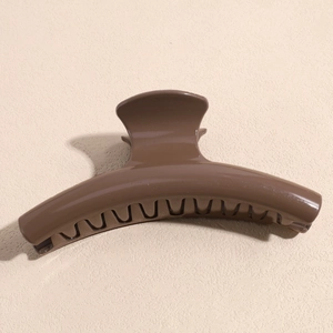 Macro view of a large glossy coffee brown hair claw clip showing teeth and metal spring