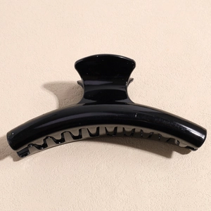 Detailed view of large glossy black claw clip showing mirror finish and curved resin teeth