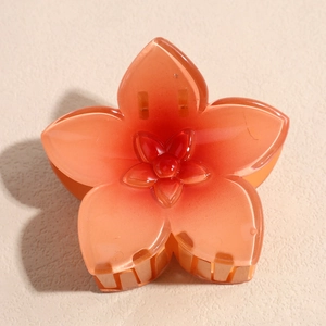 Détail de la pince à cheveux fleur dégradé orange avec une finition en résine brillante