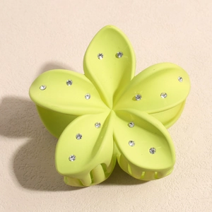 Gros plan sur une pince à cheveux fleur vert clair mat avec détails en strass brillants