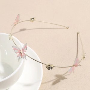 Detailed macro of golden butterfly headband with pink enamel flowers on ceramic cup
