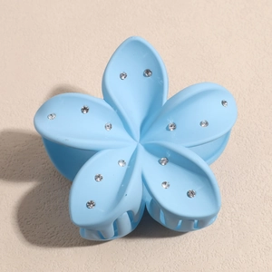 Détail de la pince à cheveux fleur bleue mate avec des strass étincelants sur les bords