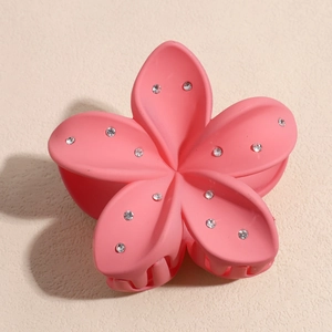 Détail d'une pince à cheveux fleur rose avec des strass brillants et une finition mate