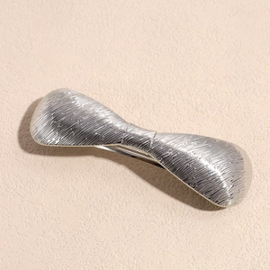 Dettaglio del fermaglio per capelli in argento a forma di fiocco con trama incisa
