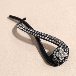 Détail d'une pince à cheveux banane noire élégante avec strass brillants au design torsadé
