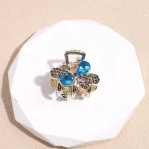 Pinza para el pelo de mariposa con pedrería y cristales azules sobre base blanca