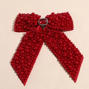 Detail of red bow hair clip featuring luxury pearls, faceted gemstone and rhinestones