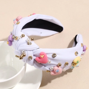 Detail of twisted white fabric headband featuring pink yellow and purple hearts with pearls