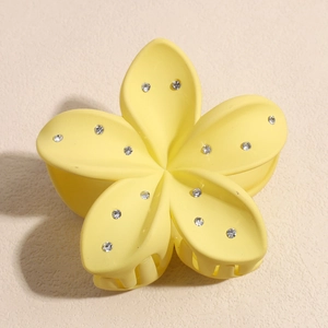 Détail de la pince à cheveux fleur de frangipanier jaune mate avec strass brillants