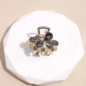 Detalle de pinza para el pelo con mariposa de diamantes de imitación en soporte geométrico