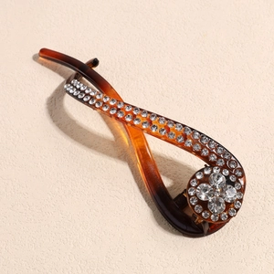Vue macro d'une pince banane en résine ambre ornée de strass brillants et décor floral