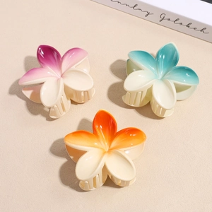 Detailed view of flower hair claws in gradient pink, blue, and orange resin finishes