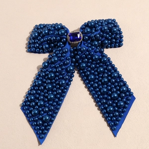 Detail of navy blue ribbon bow hair clip featuring gradient pearls and a crystal centerpiece