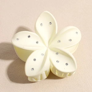 Détail d'une pince à cheveux fleur crème ornée de strass avec une finition mate