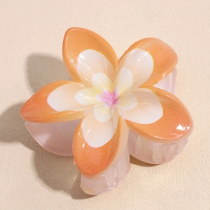 Détail d'une pince à cheveux fleur de frangipanier avec dégradé orange et fini nacré