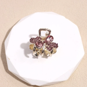 Vista macro de una pinza para el pelo dorada con lazo de diamantes de imitación púrpuras