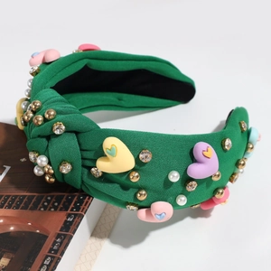 Close-up of green knotted headband with colorful hearts, pearls and sparkling crystals