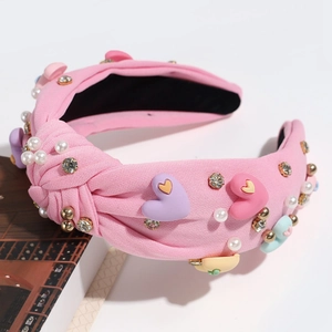 Detail of pink fabric knotted headband with pearls, rhinestones, and heart ornaments