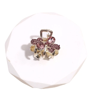Elegante pinza de pelo plateada con diamantes de imitación púrpuras sobre base blanca