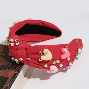 Detail of red knotted headband with colorful heart charms, pearls, and sparkling rhinestones