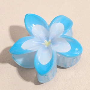 Vue détaillée d'une pince à cheveux en fleur dégradée bleue avec finition résine