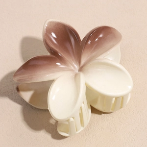 Close-up of a floral hair claw clip featuring cream to pink gradient resin and glossy finish