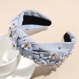 Detail of light blue knotted headband with white daisy flowers and faux pearls texture