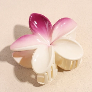 Close-up of plumeria hair claw clip with cream and purple gradient on textured background