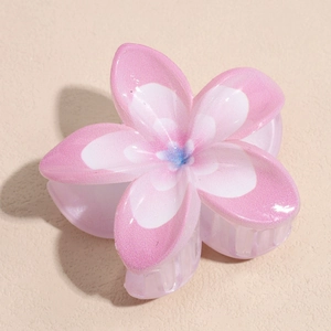 Détail macro d'une pince à cheveux fleur de frangipanier dégradée rose avec effet perlé