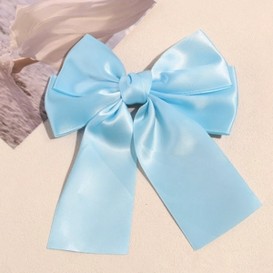 Detail view of light blue satin double bow hair clip with flowing long ribbons