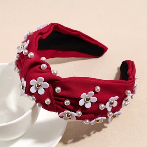 Detail of red knotted wide headband with delicate pearl accents and small white floral decor