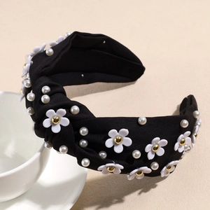 Detailed view of black knotted headband with white flower charms and faux pearls