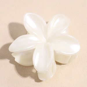 Détail d'une pince à cheveux en forme de fleur de lys blanc nacré au fini résine brillant