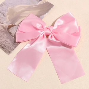 Close-up of pink satin double-layered bow hair clip with elegant silky fabric texture