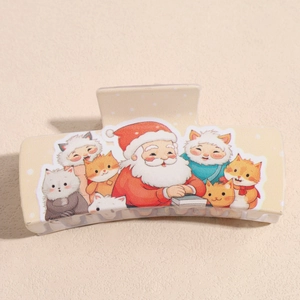 Detail of Christmas claw clip featuring cartoon Santa and cats on beige acrylic surface