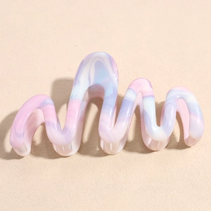 Detail of wavy hair claw clip with pink blue and purple marble texture resin finish